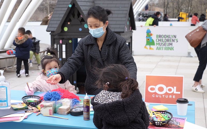 Creating Healing Spaces at our March Wellbeing Jamboree 1 Caregiver and two children work with yarn and markers at a craft table.